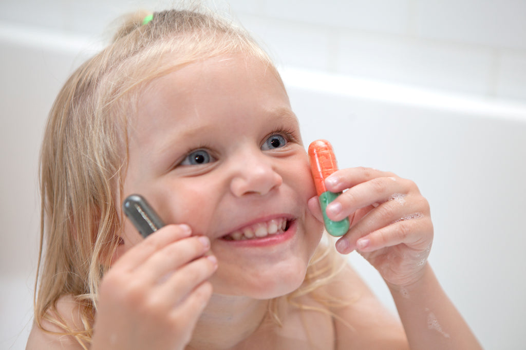 Smiling girl in the bath holding Bath Beans capsules