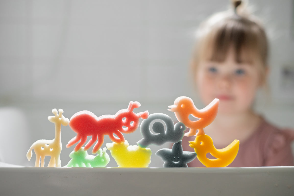 Sponge animal toys lined up along the edge of a bath