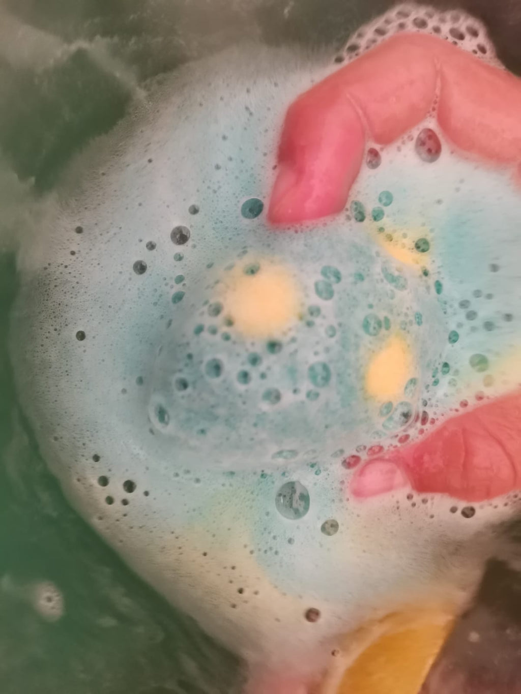 Child's hands holding a spotted Egg Bath Bomb Sprudel fizzing in the bath