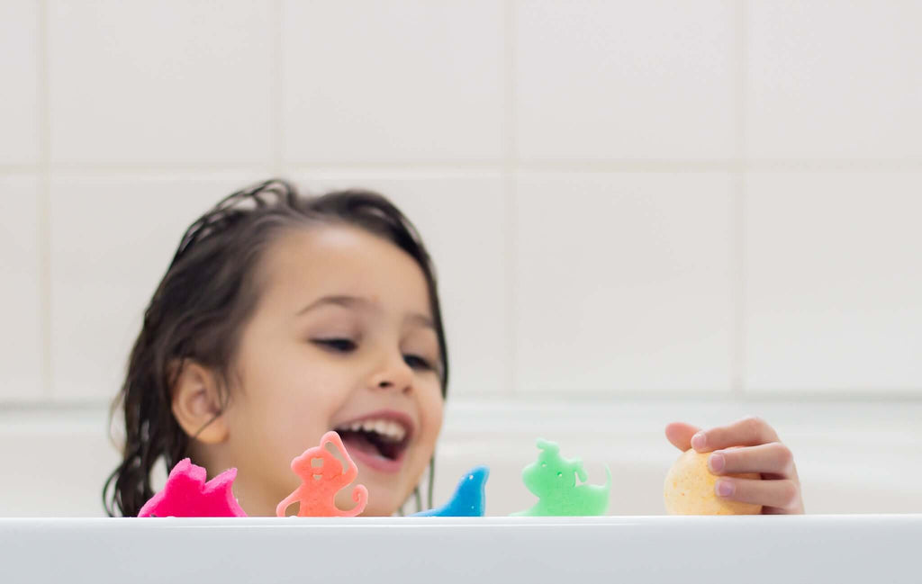 Little girl smiling in the bath with colourful bath toys