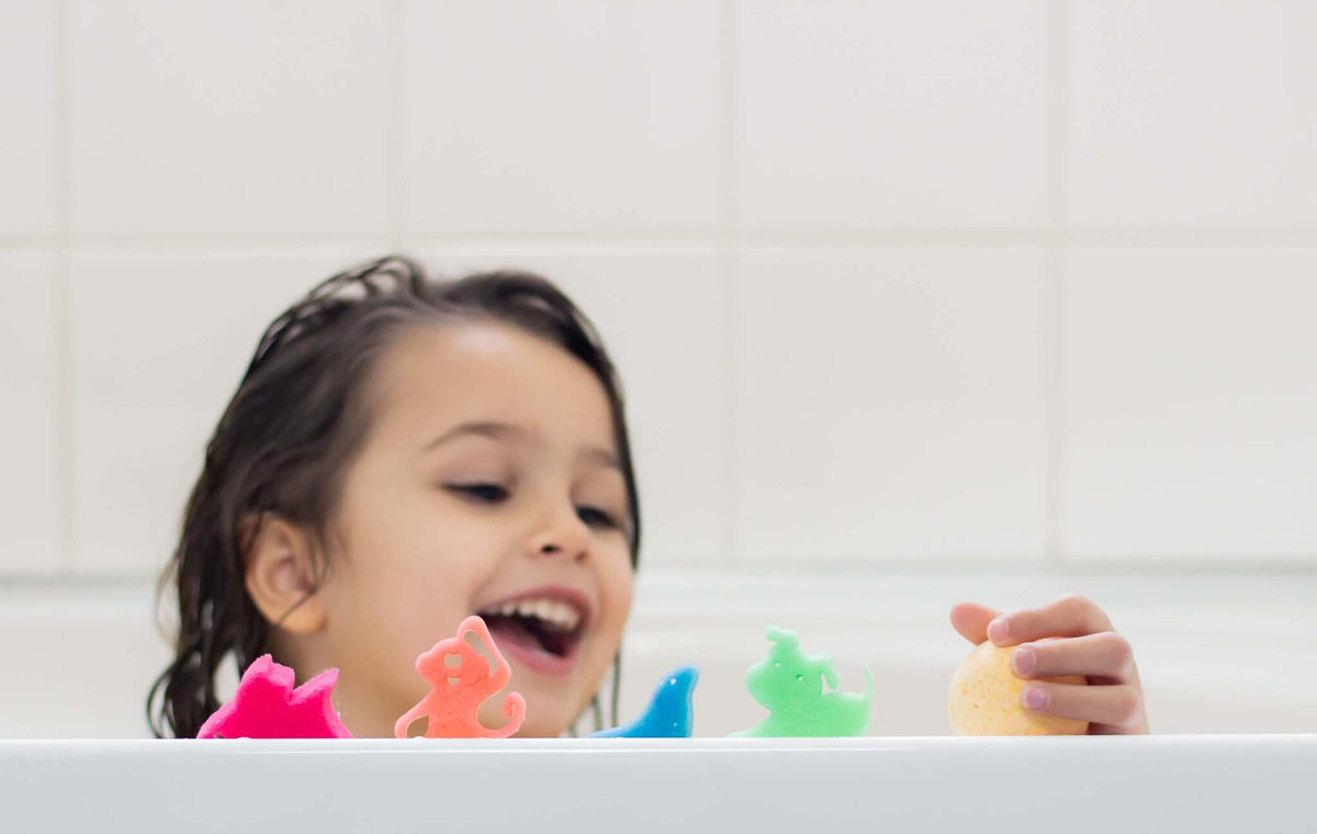 Little girl smiling in the bath with colourful bath toys