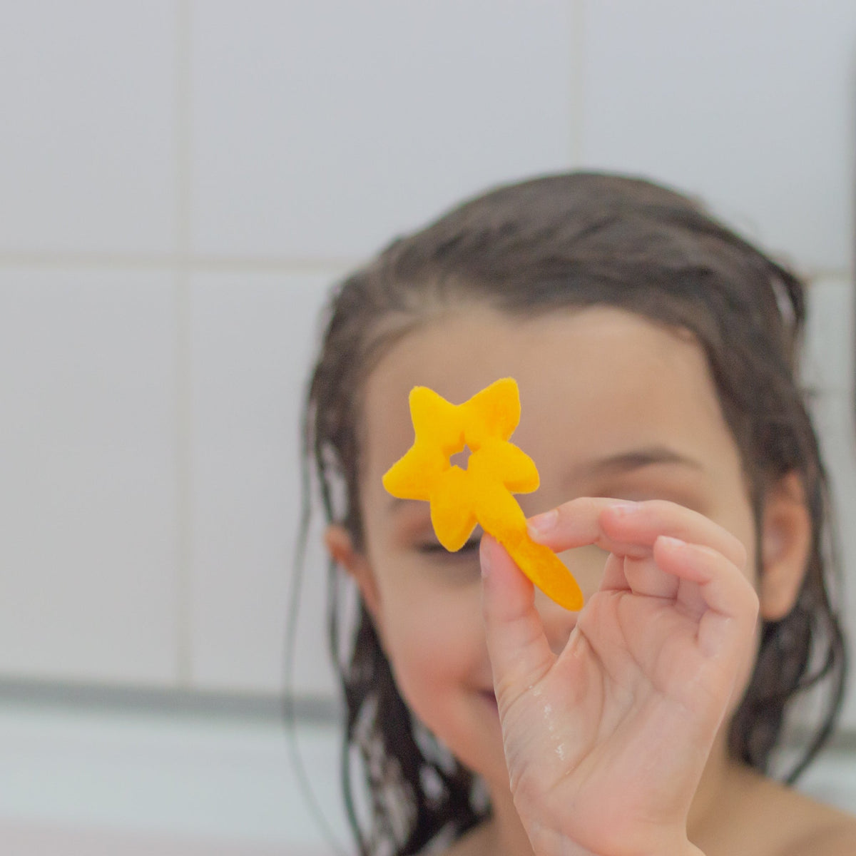 Child holding a yellow star wand sponge toy
