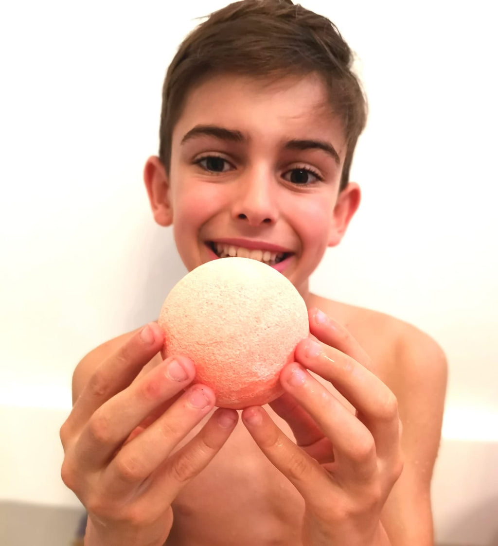 Smiling boy in the bath holding a Jumbo Bath Bomb Sprudel