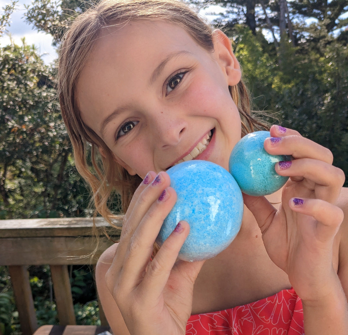 Smiling girl holding a blue Jumbo Bath Bomb Sprudel and a smaller bath bomb