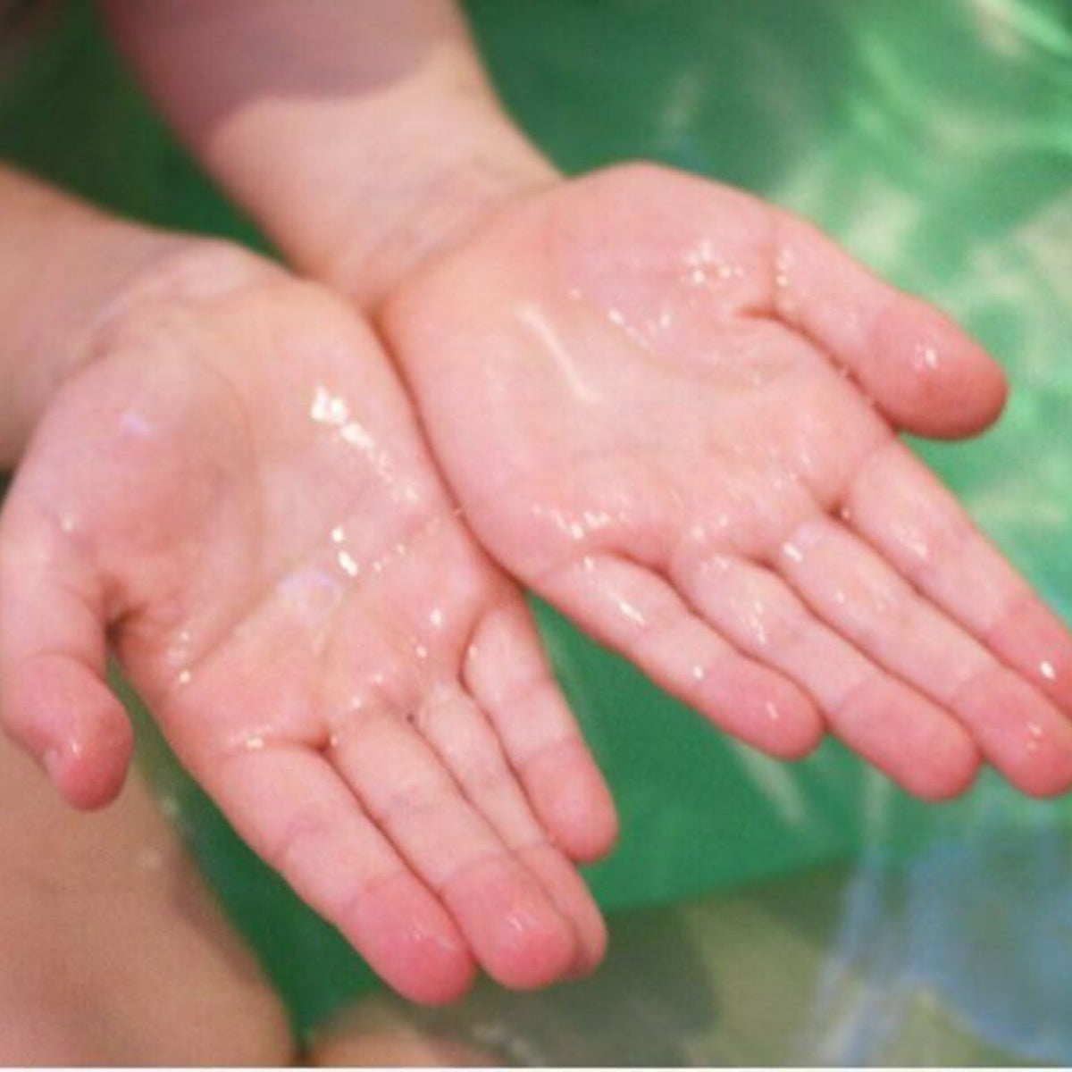 Child's clean hands in bath water after a kids bath bomb, with no staining