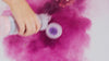 bath sprinkles shaker with purple powder mixing in water